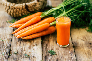 Fresh carrots with stem and leaves on a wooden background, carrot juice, vegetables harvest