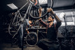 © Fxquadro - Two attractive repairmans are fixing broken bicycle at their dark workshop.