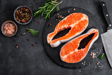 Raw salmon fish steaks on black background