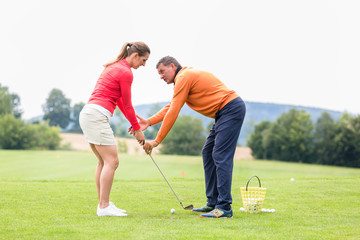 Wall Mural - Golfer giving training to woman for taking a shot