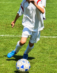 Young soccer player runs with a ball