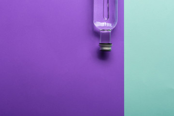 transparent wineglass and bottle with water on bright purple and azure background