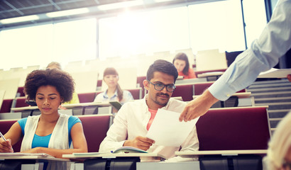 Canvas Print - education, high school, university, learning and people concept - teacher giving tests to students at lecture