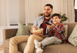© Syda Productions - family, childhood, fatherhood, technology and people concept - happy father and little son with popcorn and remote control watching tv at home in evening