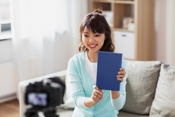 blogging, technology, videoblog and people concept - happy smiling asian woman or blogger with camera recording video blog of book review at home