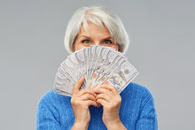 Savings, Finances And People Concept - Smiling Senior Woman Hiding Face Behind Hundreds Of Dollar Money Banknotes