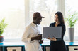 © F8  \ Suport Ukraine - African business man and caucasian woman with laptop in a modern business center.
