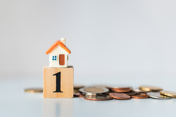 Miniature house on number one wooden block with stack coins using as property invesment and business concept