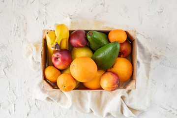 Wall Mural - big wooden crate with ripe fresh fruits, banana, apple, orange, mandarine, avocado, vegeterian foods