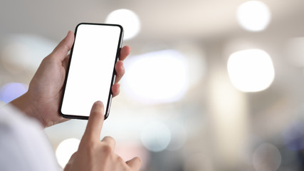 Woman holding and touching blank screen smartphone in bokeh background
