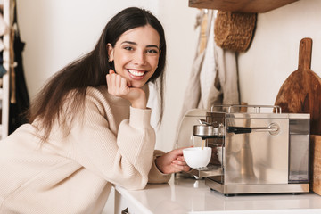 Wall Mural - Lovely young girl having cup of coffee at the kitchen