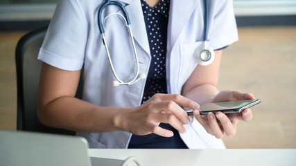 Cropped image of female doctor texting and using on smartphone