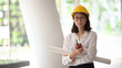 © bongkarn - Portrait of Asian attractive female constructor with blueprints in office