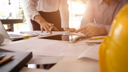 Architect designers discuss the sketches blueprint at working construction site