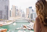 Fototapeta Miasta - Woman in Dubai Marina, United Arab Emirates. Attractive lady wearing a long dress admiring Marina daylight views