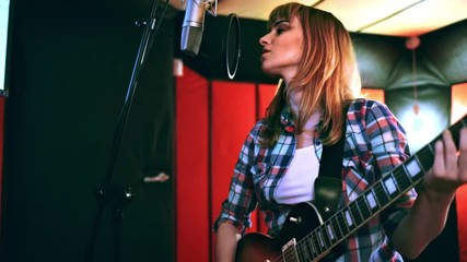 Wall Mural - Young singer with guitar singing a song in recording studio