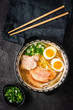 Japanese Ramen Soup with Udon Noodles, Pork, Eggs and Scallion on dark Stone Background