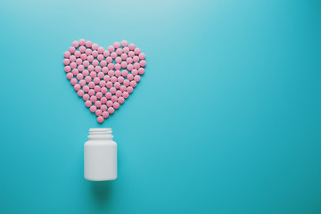 Pink B12 pills in the shape of a heart on a blue background, poured out of a white can Low contrast