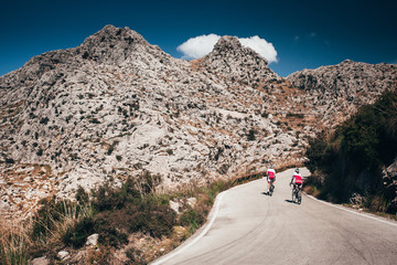 Wall Mural - Man and woman ride together on road bicycle. Adventure in big mountains