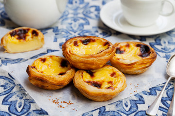 Egg tart, traditional Portuguese dessert, pastel de nata on a parchment paper. Blue background.