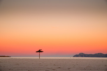 Umbrella on the morning beach. Beautiful colorful summer sunrise