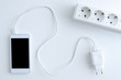White smartphone with battery charging cable and power outlet.