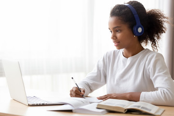 Wall Mural - African American teen girl wearing headphones learning language online