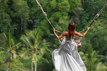 Woman In Long White Dress Swinging In The Jungle, Bali