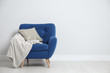 © New Africa - Stylish armchair with pillow and plaid near white wall, space for text. Interior design