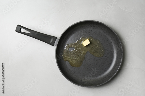 Cuadros en Lienzo Frying pan with melting butter on grey table, top view