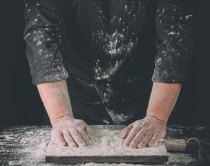 cook  put two hands on a table sprinkled with white wheat flour