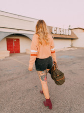 Woman Carrying Brown Bag Walking Towards Red Door