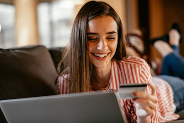 Young woman at home makes a purchase on the Internet on the laptop with credit card