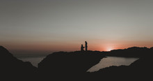 Silhouette Of Man Proposing To Woman On Rock Formation