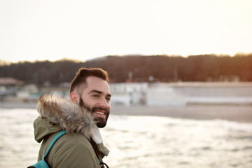 Wall Mural - Stylish young man with backpack near sea