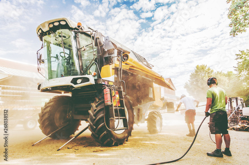 Fotografía The mechanics repair the yellow and green combine harvester in the farm yard