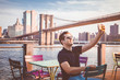 Tourist handsome male model taking a selfie near a Brooklyn Bridge