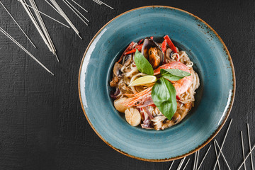 Wall Mural - Pasta spaghetti with seafood, langoustine, mussels, oysters, squid in mushrooms sauce on plate over dark stone background. Italian food.