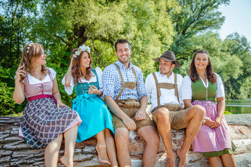 Five friends having fun on Bavarian RIver and clinking glasses with Oktoberfest beer