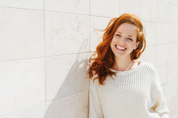 Smiling young woman near white wall