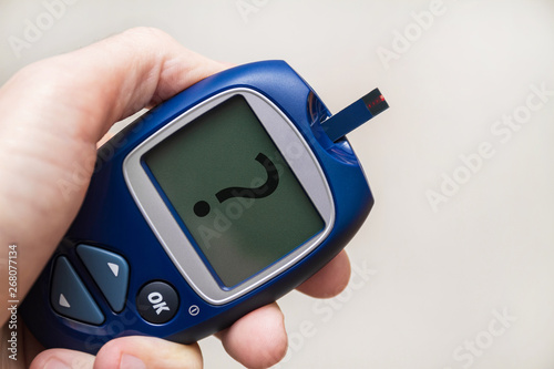 Fotografía Man holding glucometer with test strip with question mark on the monitor