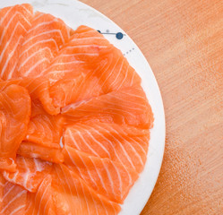 Wall Mural - Closeup top view Slided Raw Salmon in white dish on wood blackground