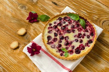 Homemade cherry pie with fresh basil decorated with flowers on wooden background