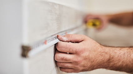 Poster - Worksman using tape measure for home renovation.