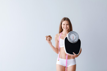 Sticker - Beautiful young woman with coconut, scales and measuring tape on light background. Weight loss concept