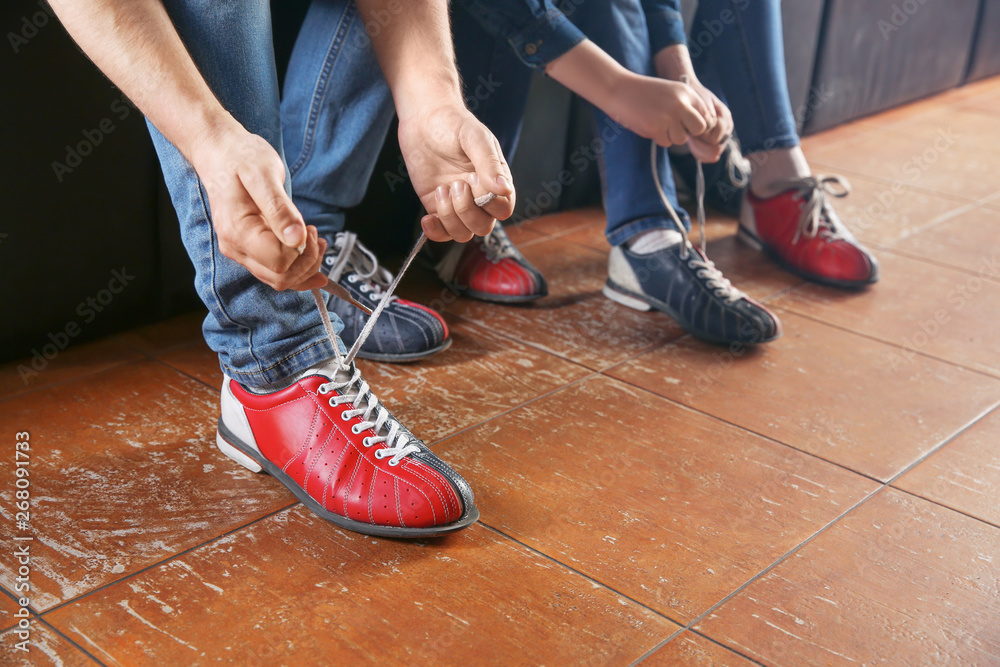 Family changing shoes before playing bowling in club