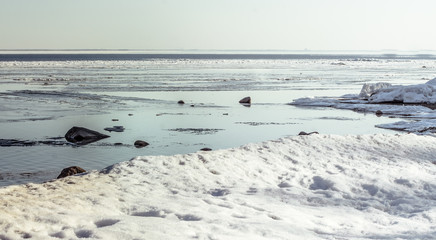 Snow pile, hill. Large snow drift isolated on a blue sky background,  outdoor view of ice blocks at frozen finland lake in winter