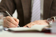 © Тихон Купревич - Male arm in suit and tie hold silver pen filling schedule in notepad at office workplace closeup. Legal law consult assistance gesture or finance investment advisor clerk job information gesture