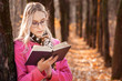© Валерий Моисеев - Beautiful girl in autumn forest reading a book. woman stand near tree and read a book