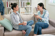 © PR Image Factory - two asian japanese women friends having coffee and looking at each other sitting on couch. girls having fun relax on sofa laughing loudly drinking tea. female roommates talking about funny life thing